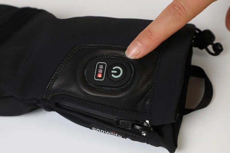 Nahaufnahme des Snowlife Heat DT Glove, Finger drückt den Power Knopf mit Batteriestatusanzeige.