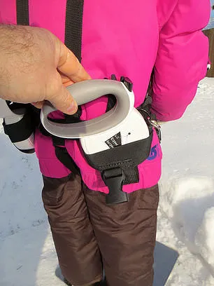 Nahaufnahme des Lil' Ripper Gripper Gurtes am Kind, mit Hand am Griff und Detail der einziehbaren Leine.
