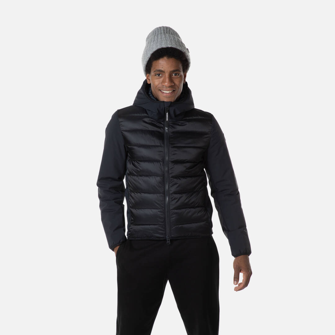 Ein Mann mit Mütze, trägt eine schwarze Rossignol Stretch Quilt Hoodie Jacke mit Kapuze.