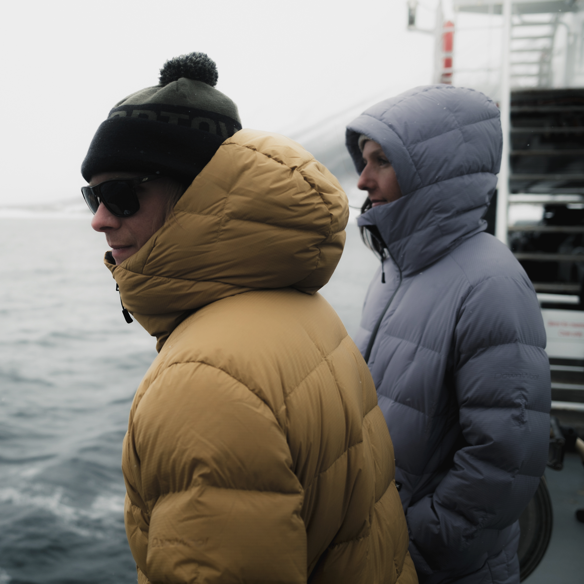 Winterliche Schiffsreise Zwei Personen, in Winterkleidung gehüllt, stehen an Deck eines Schiffes und blicken aufs Meer.