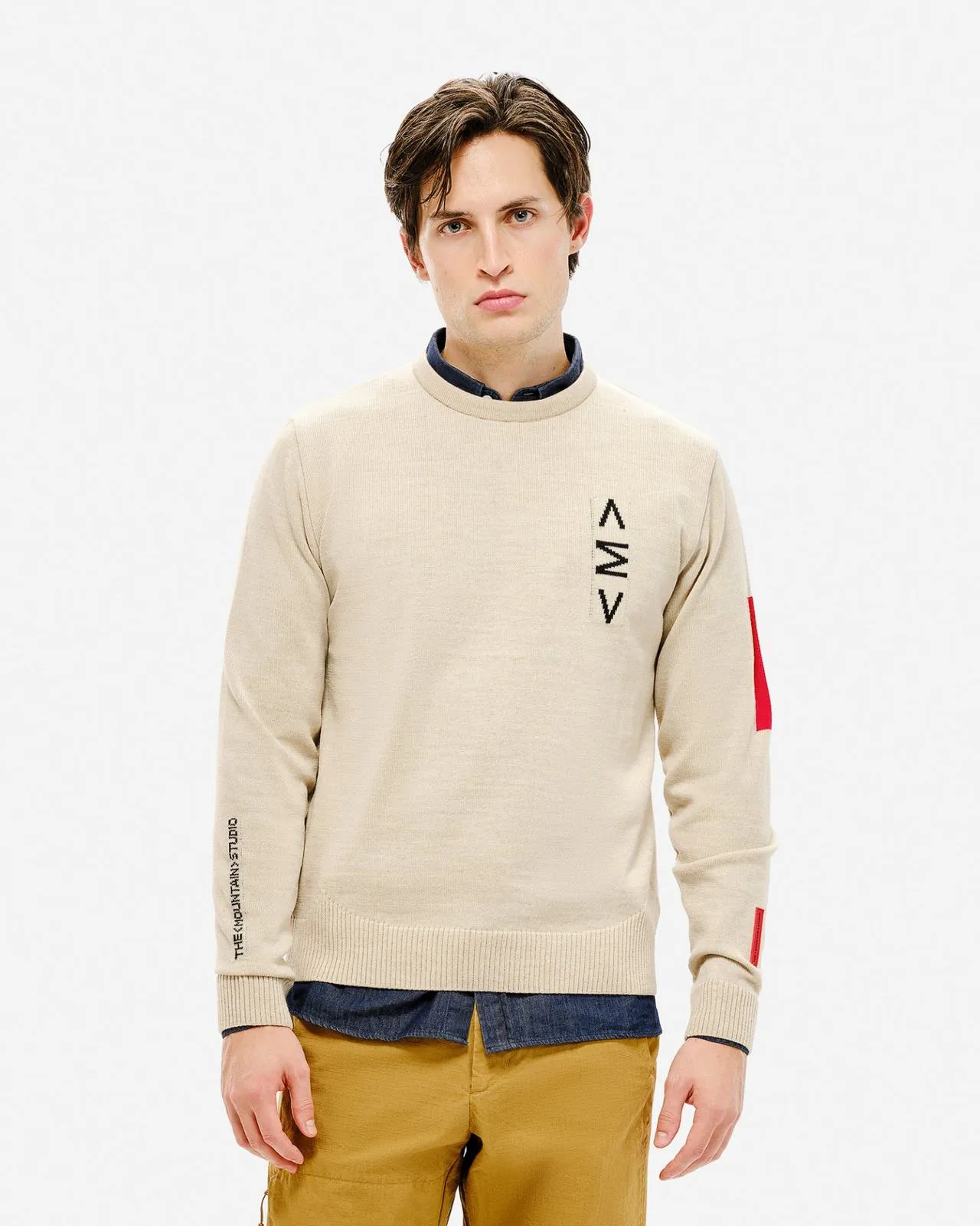 Mann trägt hellen K-3 ST Ski Sweater mit Rundhalsausschnitt, Logo und rotem Detail am Ärmel.