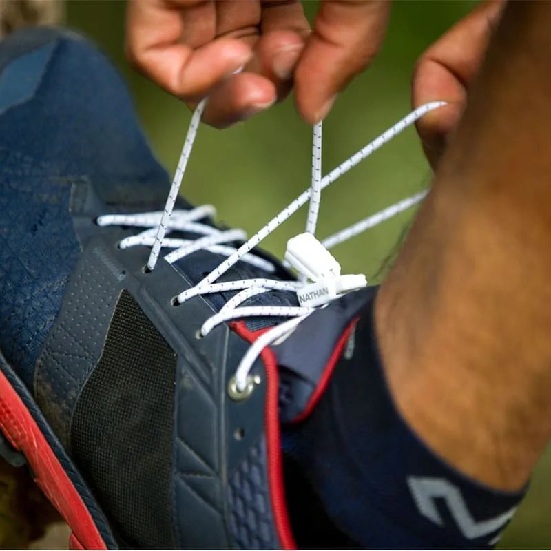 Nahaufnahme: Person bindet Run Laces an einem Laufschuh. Weiße Schnürsenkel mit Clip.