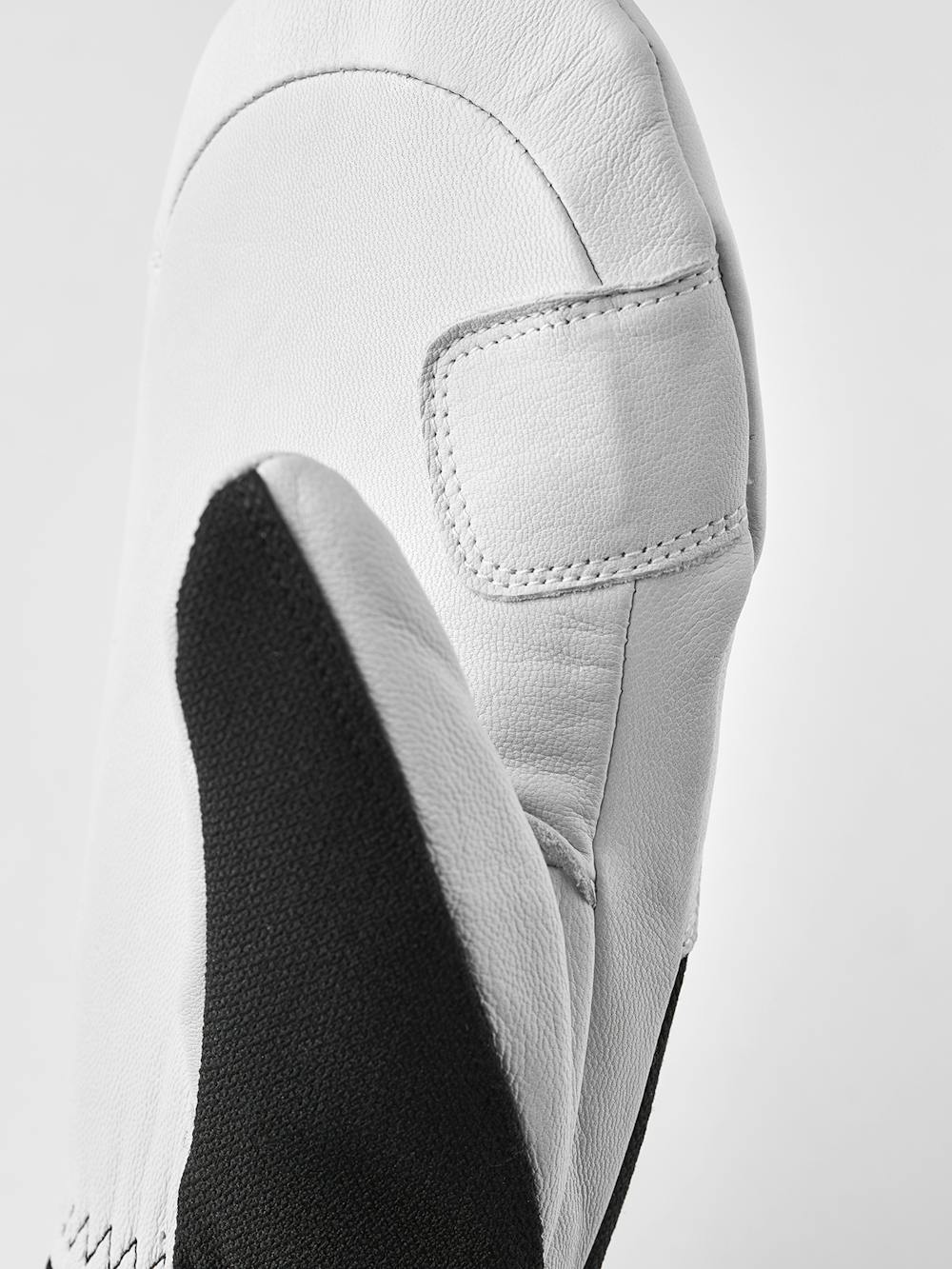 Nahaufnahme eines weißen Lederhandschuhs mit schwarzem Griffbereich, gesteppten Details und einfacher Form.