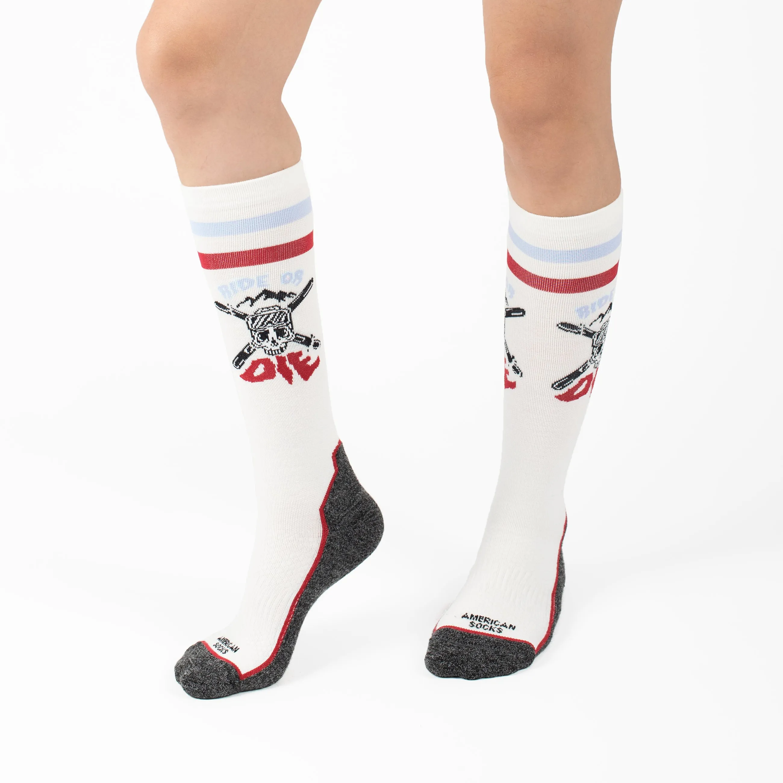 Beine mit knielangen "Ride or Die Snow Socks", weiß, Totenkopf-Motiv, grau an Zehen und Ferse.