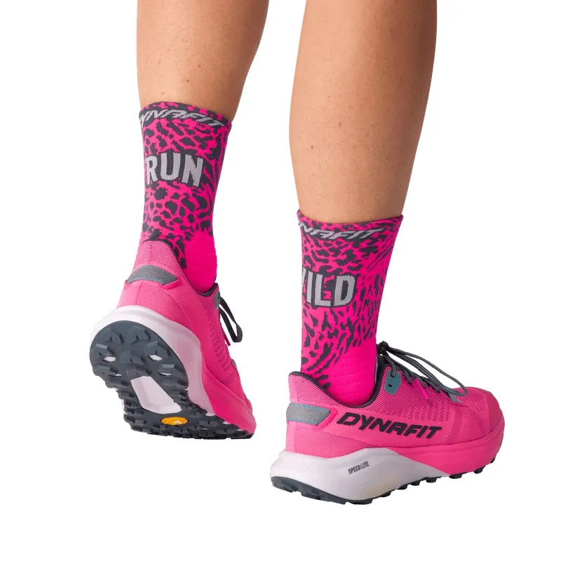 Zwei Beine tragen pinke Laufschuhe und Socken mit dem Aufdruck "RUN WILD" im Leopardenmuster.