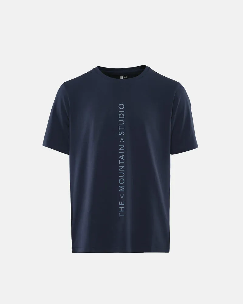 Dunkelblaues T-Shirt mit vertikalem "The Mountain Studio" Schriftzug.