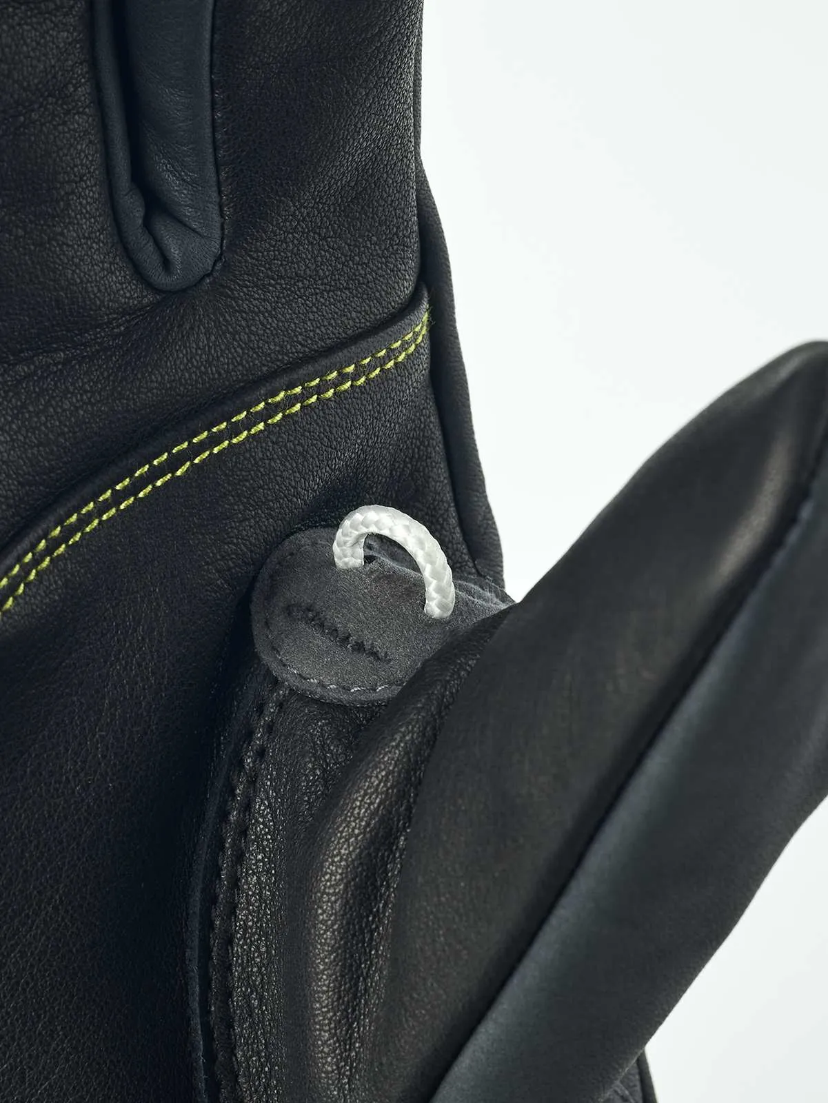 Detailansicht eines schwarzen Hestra Omni Trigger Handschuhs mit Schlaufe und gelber Naht.