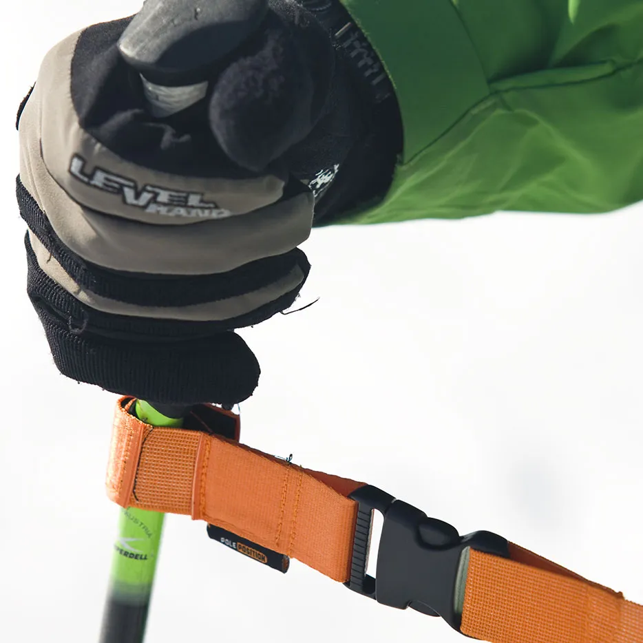 Nahaufnahme Hand mit Handschuh am Griff eines Skistocks mit orangem Training Strap.
