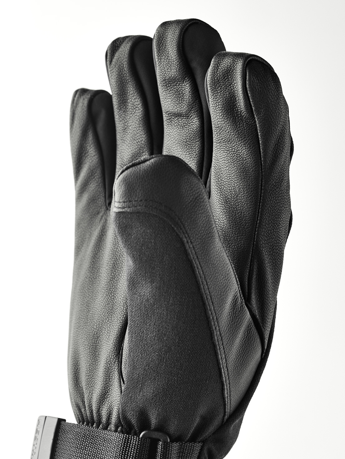 Eine schwarze Lederhandschuh mit fünf Fingern, mit einem Handgelenkband und Schnalle.