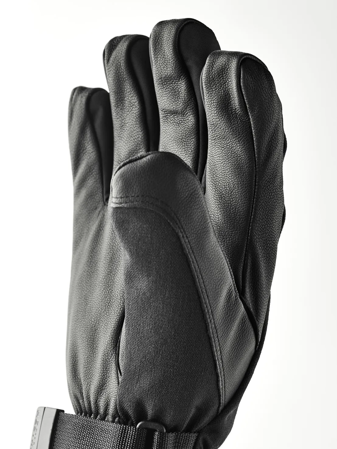 Eine schwarze Lederhandschuh mit fünf Fingern, mit einem Handgelenkband und Schnalle.