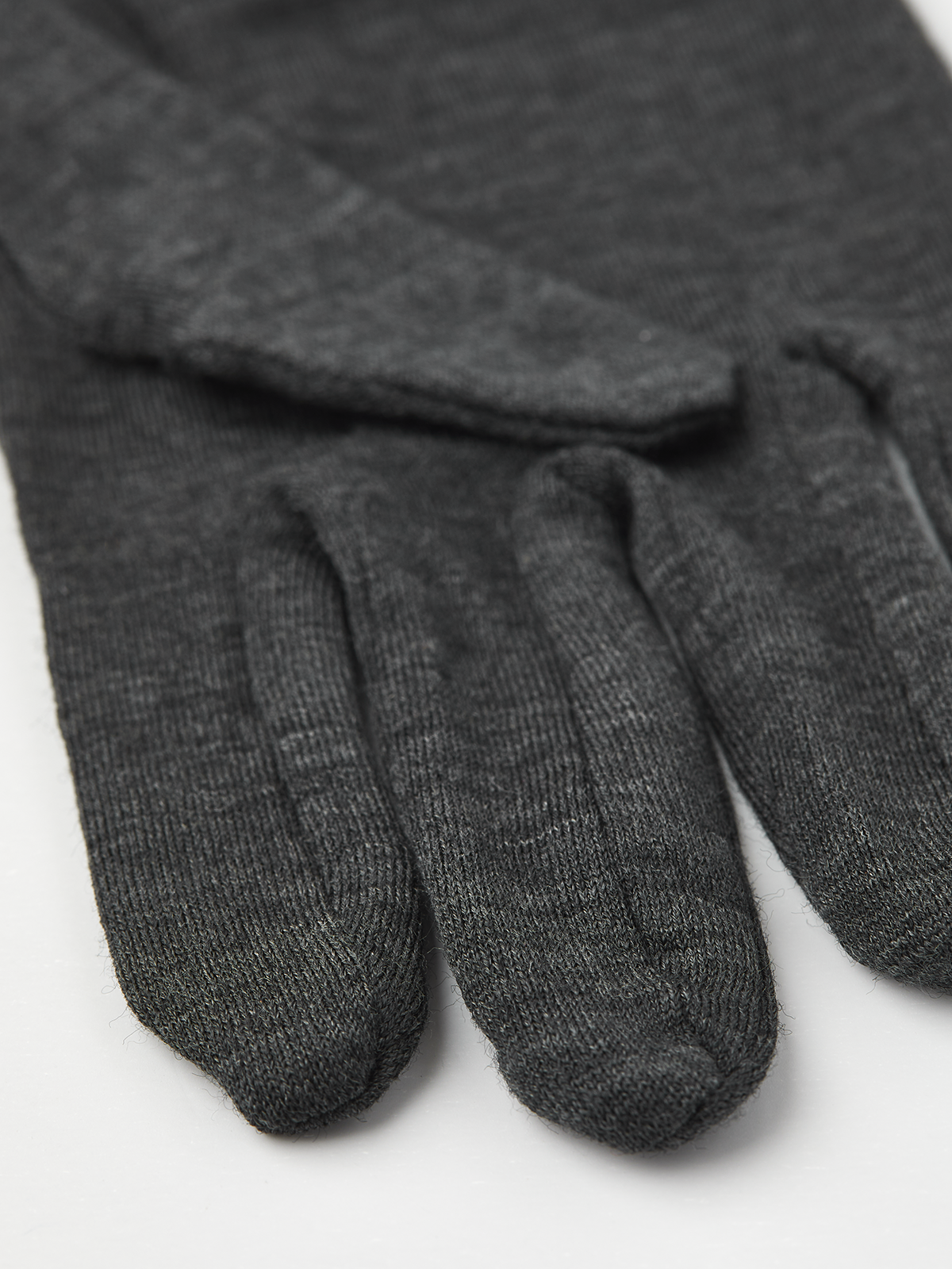 Graue Merino Wolle Handschuhe Nahaufnahme eines grauen Hestra Merino Wool Liner Active Handschuhs. Texturiertes Strickmuster sichtbar.