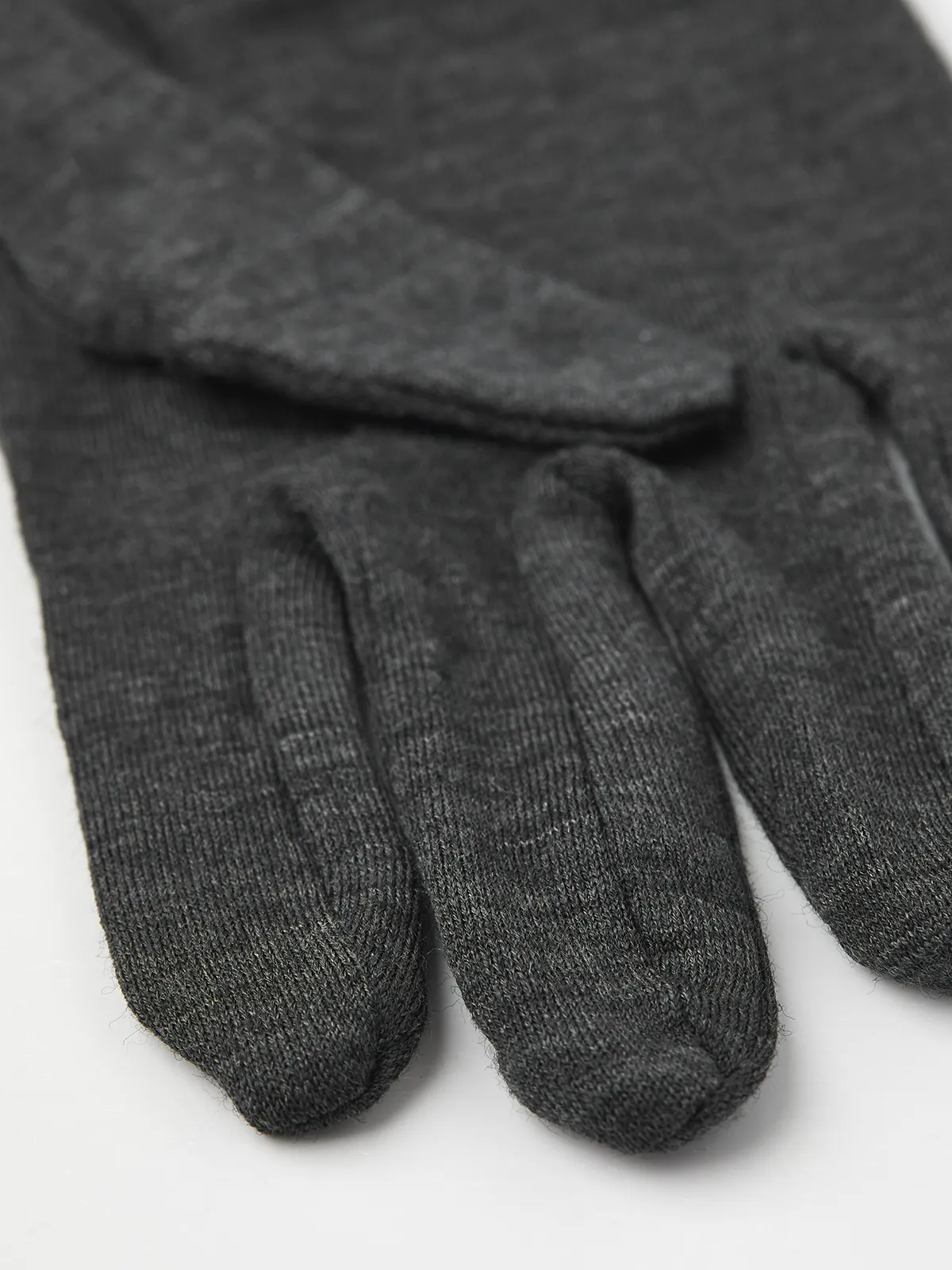 Nahaufnahme eines grauen Hestra Merino Wool Liner Active Handschuhs. Texturiertes Strickmuster sichtbar.