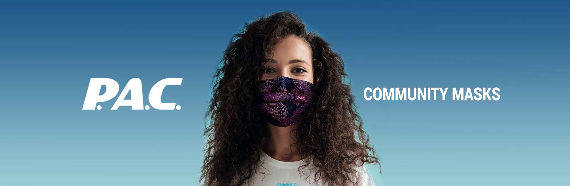 Lockige Frau mit PAC-Maske Frau mit lockigem Haar trägt eine gemusterte PAC-Maske vor blauem Hintergrund. "PAC" und "Community Masks" sind beschriftet.