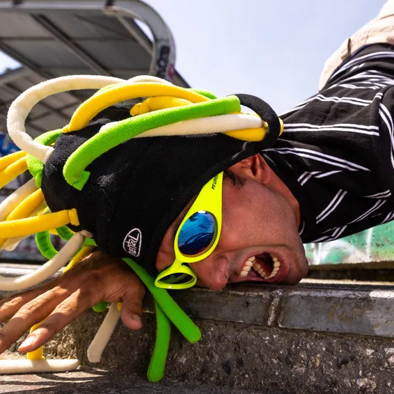 Mann mit gelber "The Sludge" Pit Viper Sonnenbrille und Rastazöpfen, auf dem Kopf stehend.