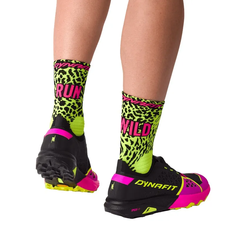 Zwei Beine mit Socken "RUN" und "WILD" im Leopardenmuster, dazu schwarze Laufschuhe mit pinkfarbener Sohle.