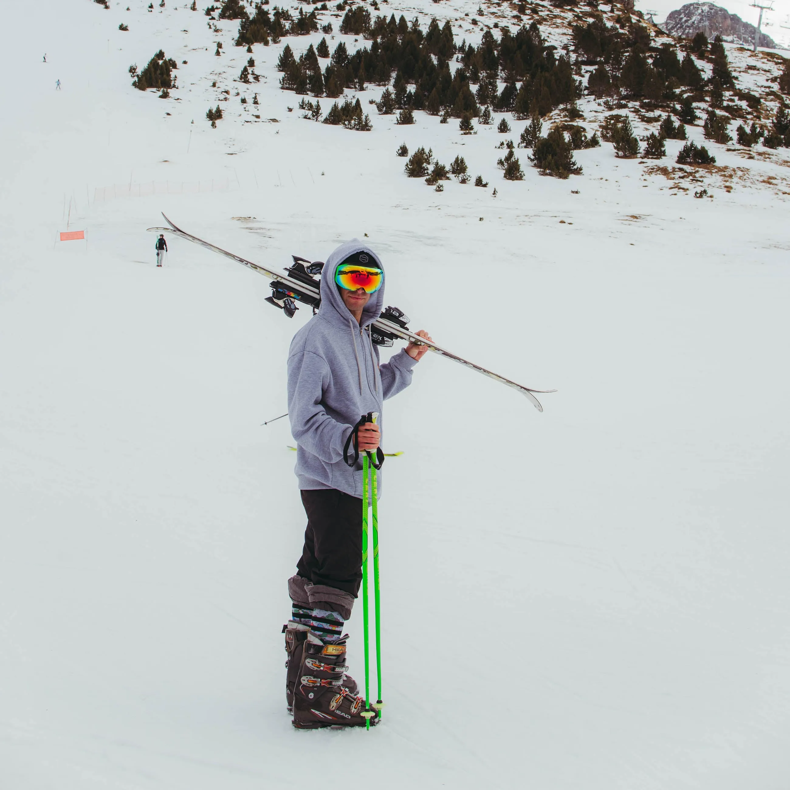 Mann mit Skiern, Skistöcken und Schneebrille auf einer verschneiten Piste. Er trägt Leaf Me Alone Snow Socks.