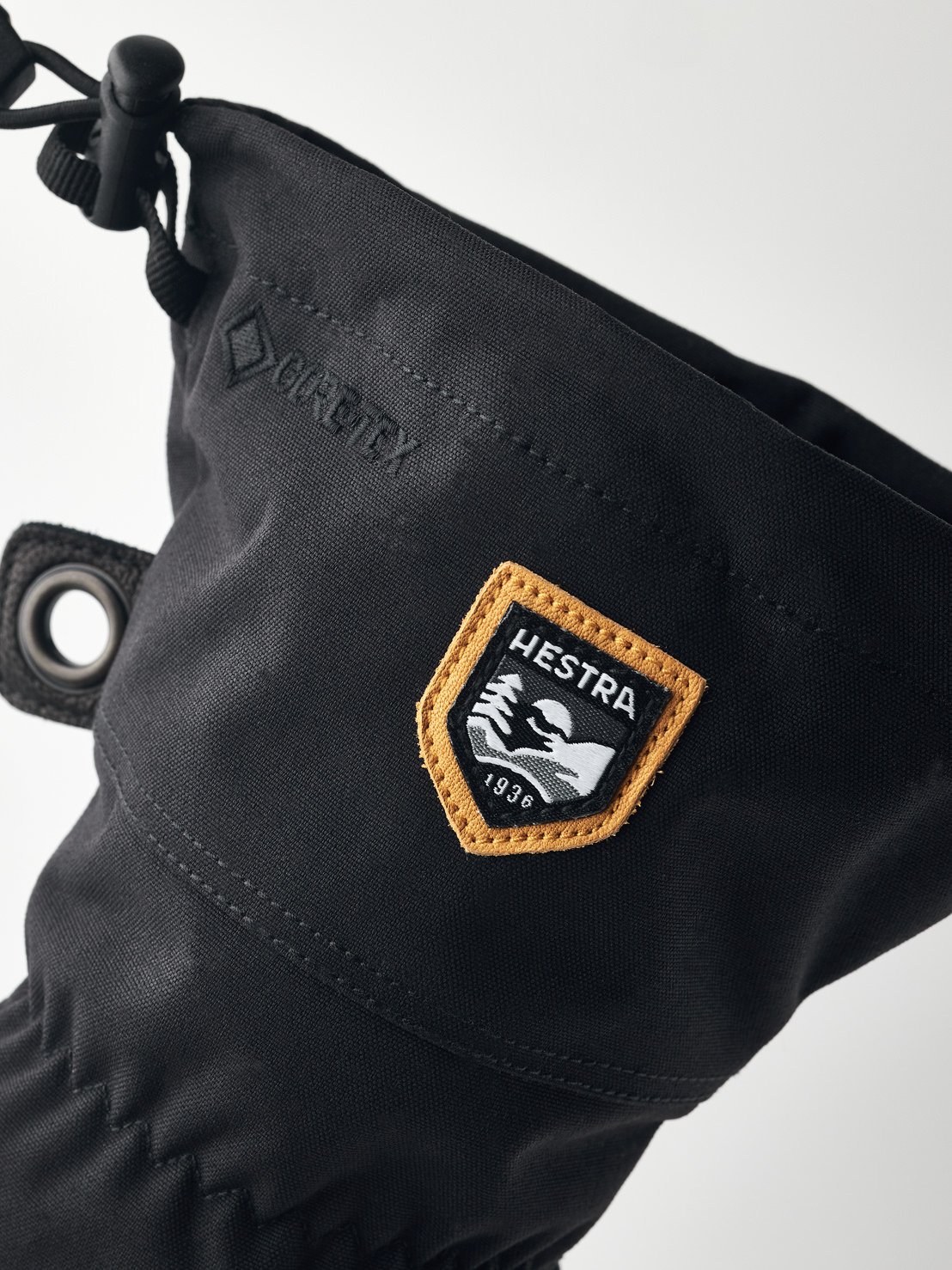 Schwarze Hestra-Handschuhe Detailansicht eines schwarzen Hestra-Handschuhs mit Gore-Tex und einem Hestra-Logo-Patch mit dem Schriftzug "1936".