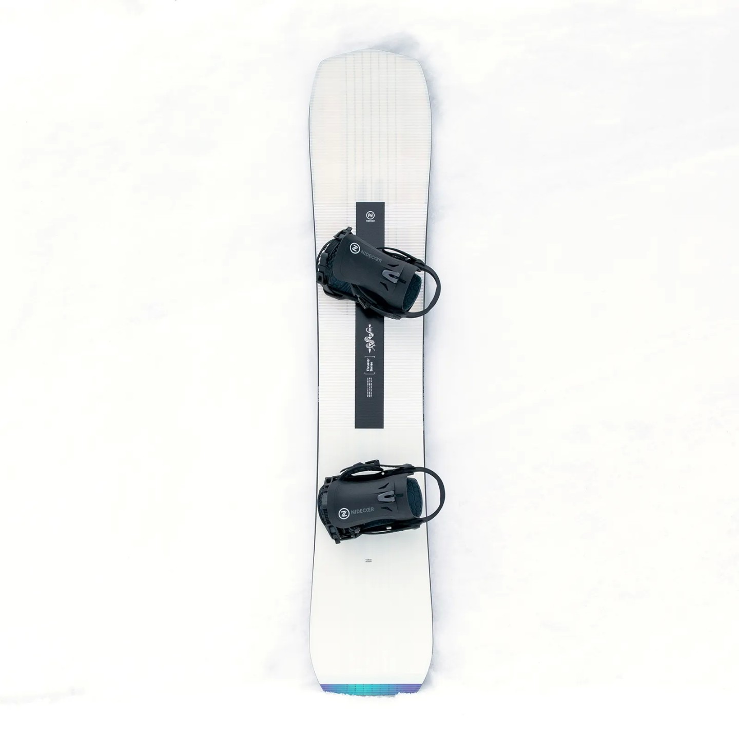 Draufsicht des Nidecker Thruster Snowboards im Schnee. Das Brett ist weiß mit schwarzen Bindungen und Grafiken.