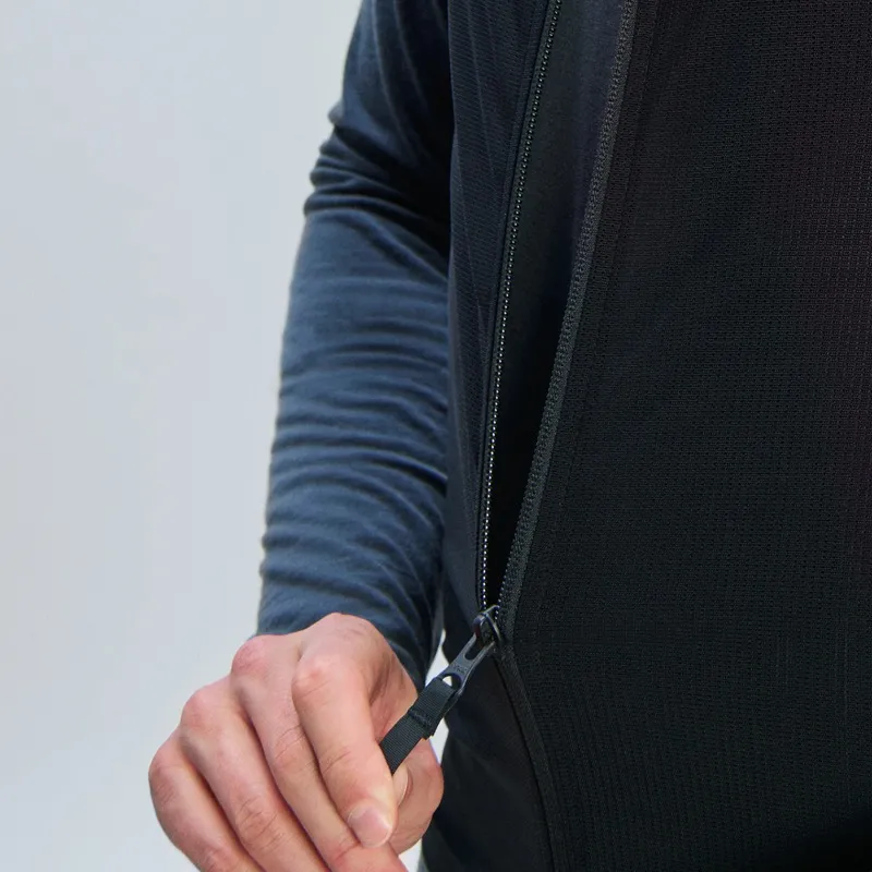 Detailaufnahme der POC VPD Air Vest in Grau, mit Reißverschluss, der von einer Hand geöffnet wird. Das Material ist luftdurchlässig.