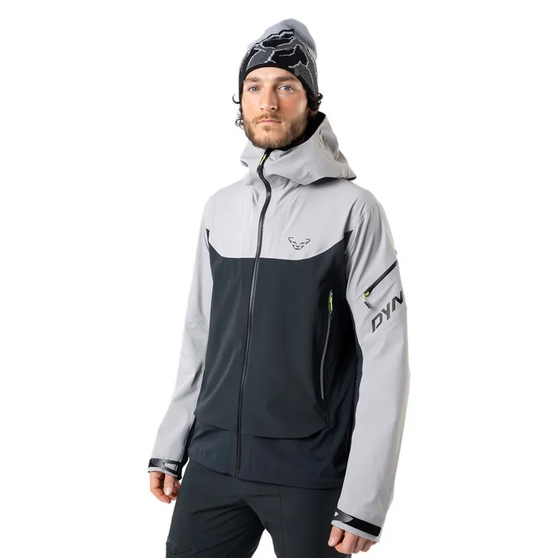 Ein Mann mit Mütze trägt eine graue Dynafit Beast Hybrid Jacke mit Kapuze.