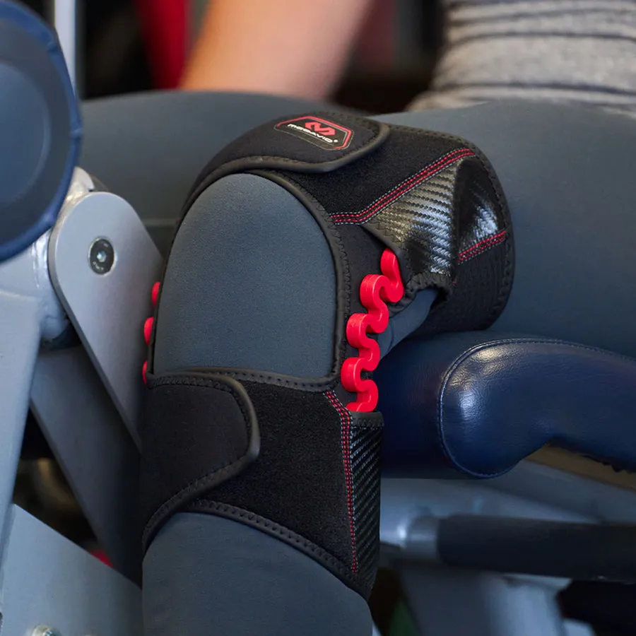 Nahaufnahme der McDavid NRG Knee Over Wrap 30590 am Knie. Die Bandage ist schwarz mit roten Details und stabilisiert das Kniegelenk.