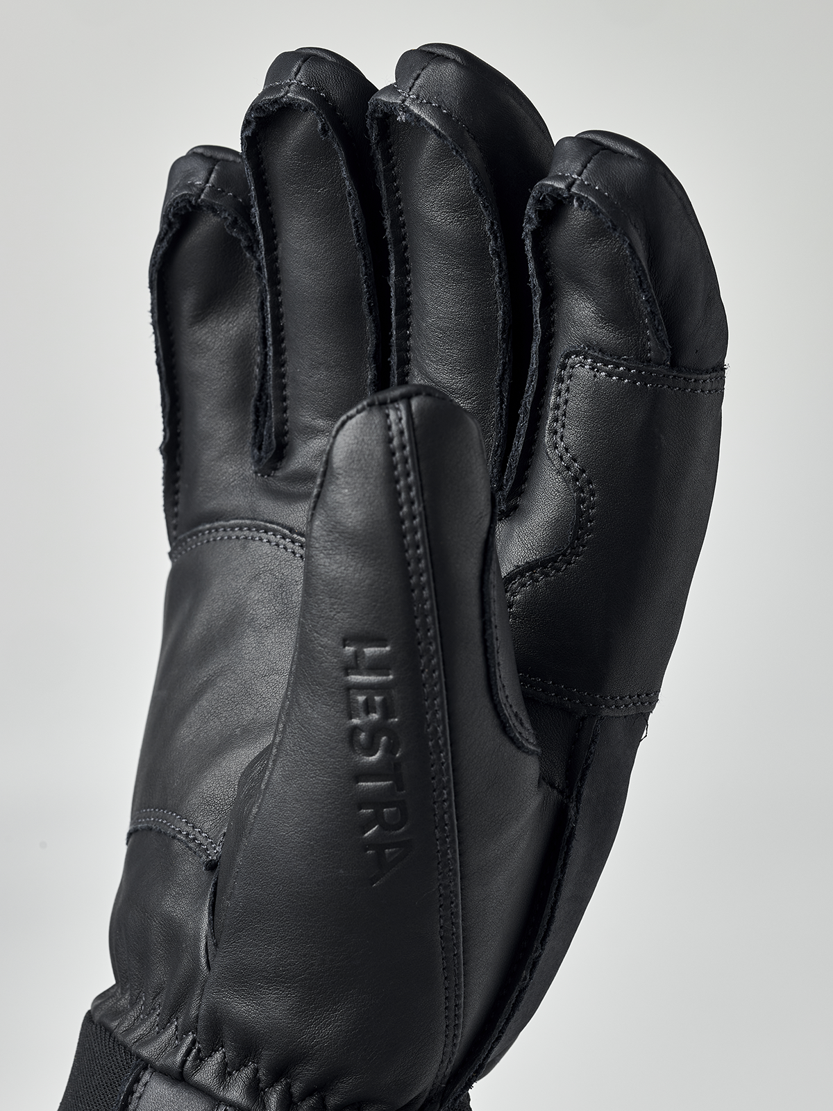 Schwarzer Hestra Fall Line Lederhandschuh aus Rindsleder, Handfläche mit eingeprägtem Schriftzug Hestra im Detail.