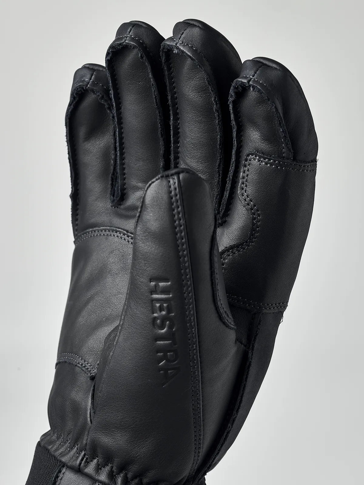 Schwarzer Hestra Fall Line Lederhandschuh aus Rindsleder, Handfläche mit eingeprägtem Schriftzug Hestra im Detail.