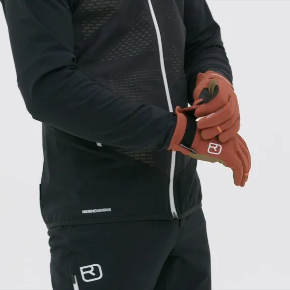 Person zieht Rock'n'Wool Glove Liner in Rotbraun an, trägt schwarze Sportkleidung.