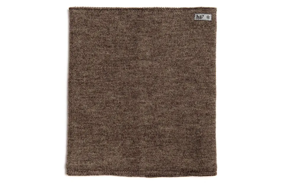 Kaki farbener, gestrickter Merino Neckwarmer, flachliegend. Ein kleines Markenlabel ist oben rechts angebracht.