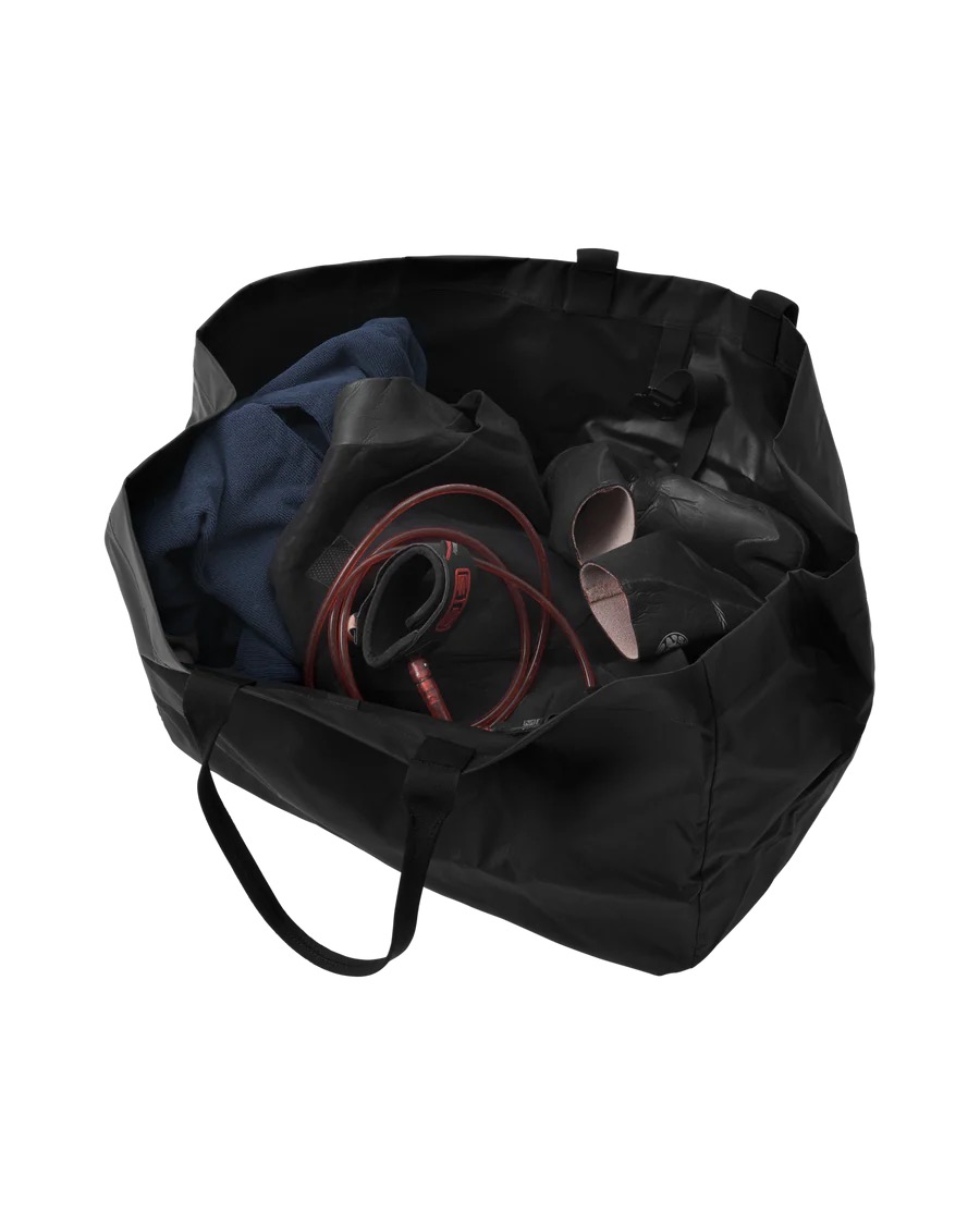 Surf Essential Tote 80L Schwarze, offene Surf Essential Tote 80L gefüllt mit Kleidung, Schuhen und einer Trinkblase.