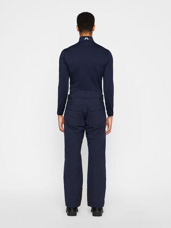 Marineblaue Skihose Rückansicht Rückansicht einer Person in marineblauen Truulli Skihose und Oberteil von J.Lindeberg vor einem weißen Hintergrund.