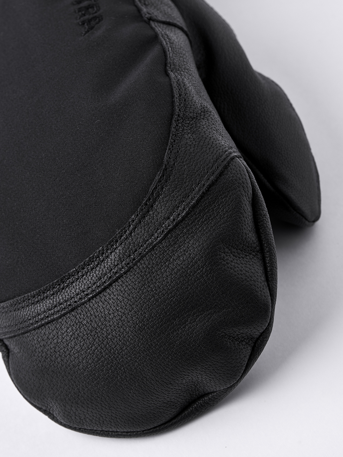Nahaufnahme eines schwarzen Hestra Army Leather Extreme Mitt Fäustlings. Leder an der Handfläche, Textil am Handrücken.