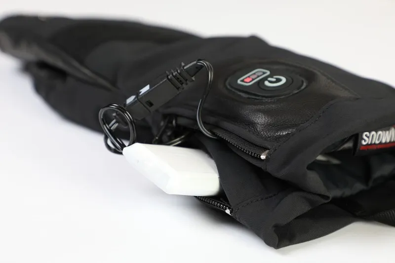 Nahaufnahme eines schwarzen Heat DT Glove mit Bedienfeld, Akku und USB-Kabel.