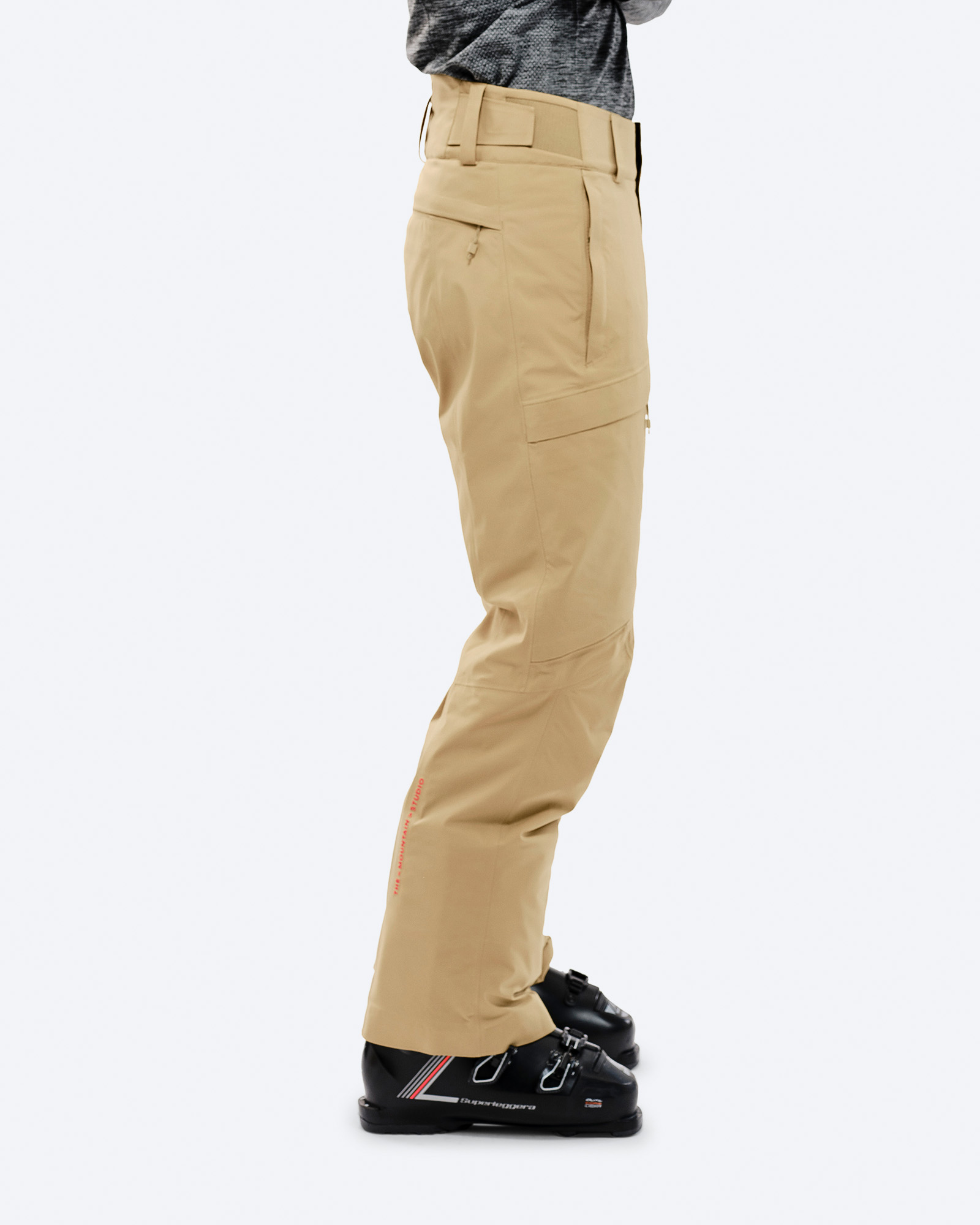 Sandfarbene GORE-TEX 2L Stretch Skihose am Körper mit Skischuhen, Seitenansicht.