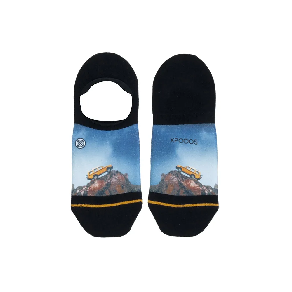 Zwei XPOOOS Socken; Motiv: Geländewagen auf Berggipfel, blauer Himmel. Schwarze Socke mit gelben Streifen.