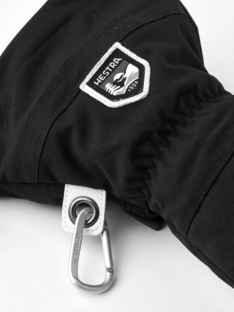 Detailaufnahme eines schwarzen Handschuhs mit Hestra-Logo, weißer Schlaufe und Karabinerhaken.