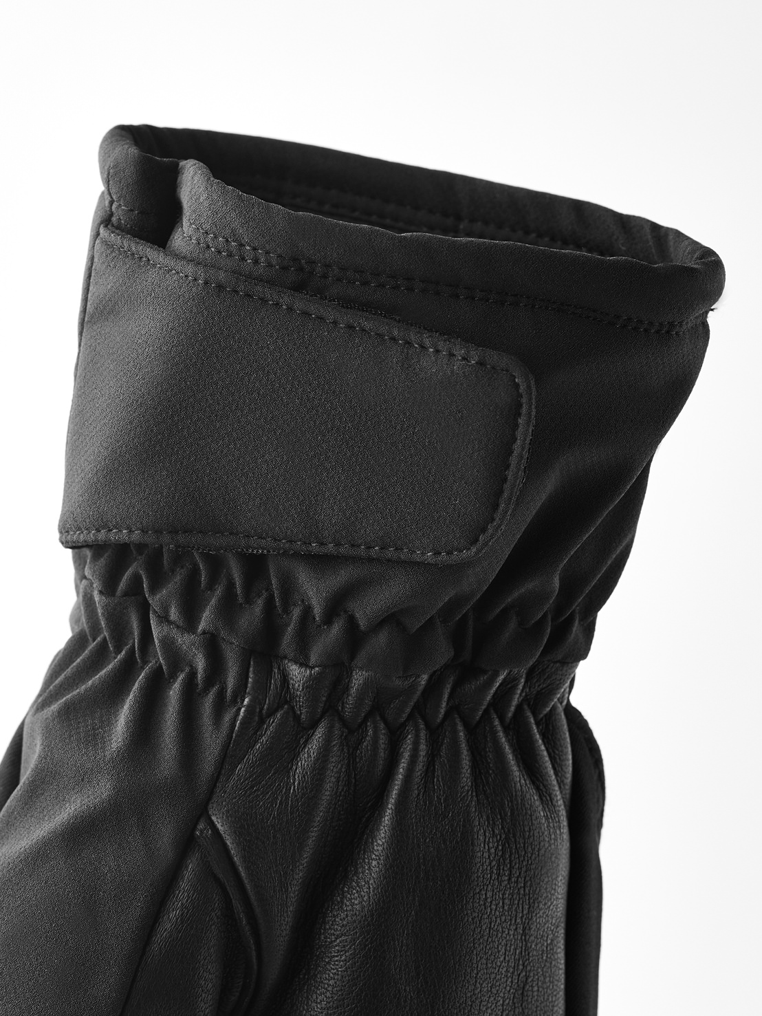 Nahaufnahme eines schwarzen Winterhandschuhs, mit verstellbarem Riemen am Handgelenk und elastischem Bund.