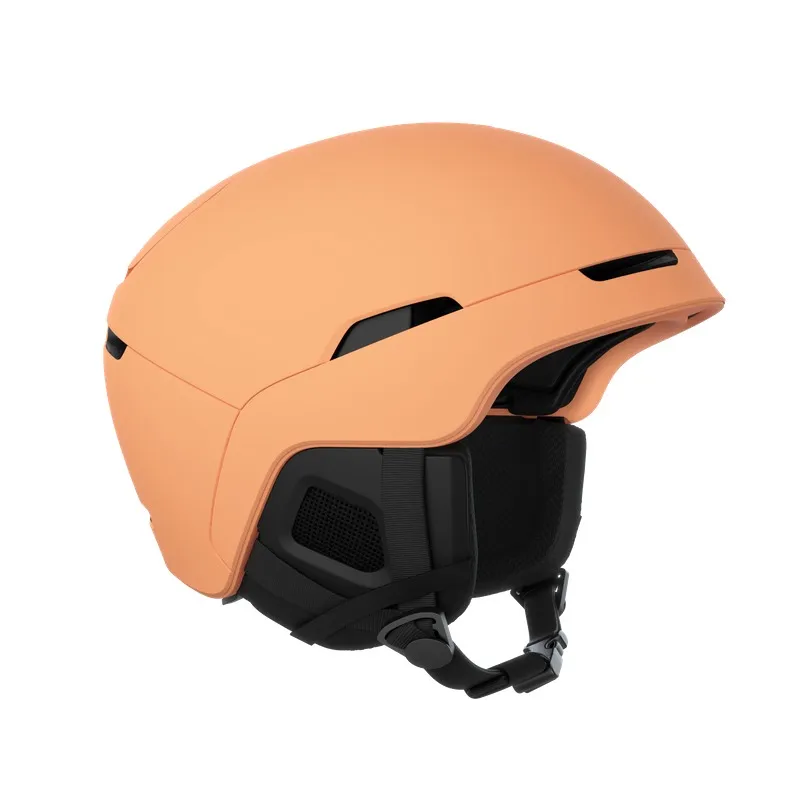 Pfirsichfarbener Skihelm mit schwarzen Akzenten und Kinnriemen, isoliert auf einem weißen Hintergrund.
