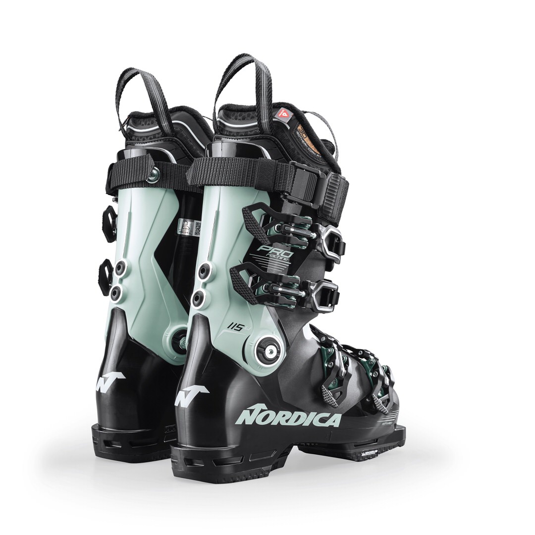 Zwei Nordica Pro Machine 115 Damen Skischuhe in Schwarz und Hellgrün, von hinten fotografiert, isoliert auf weißem Grund.