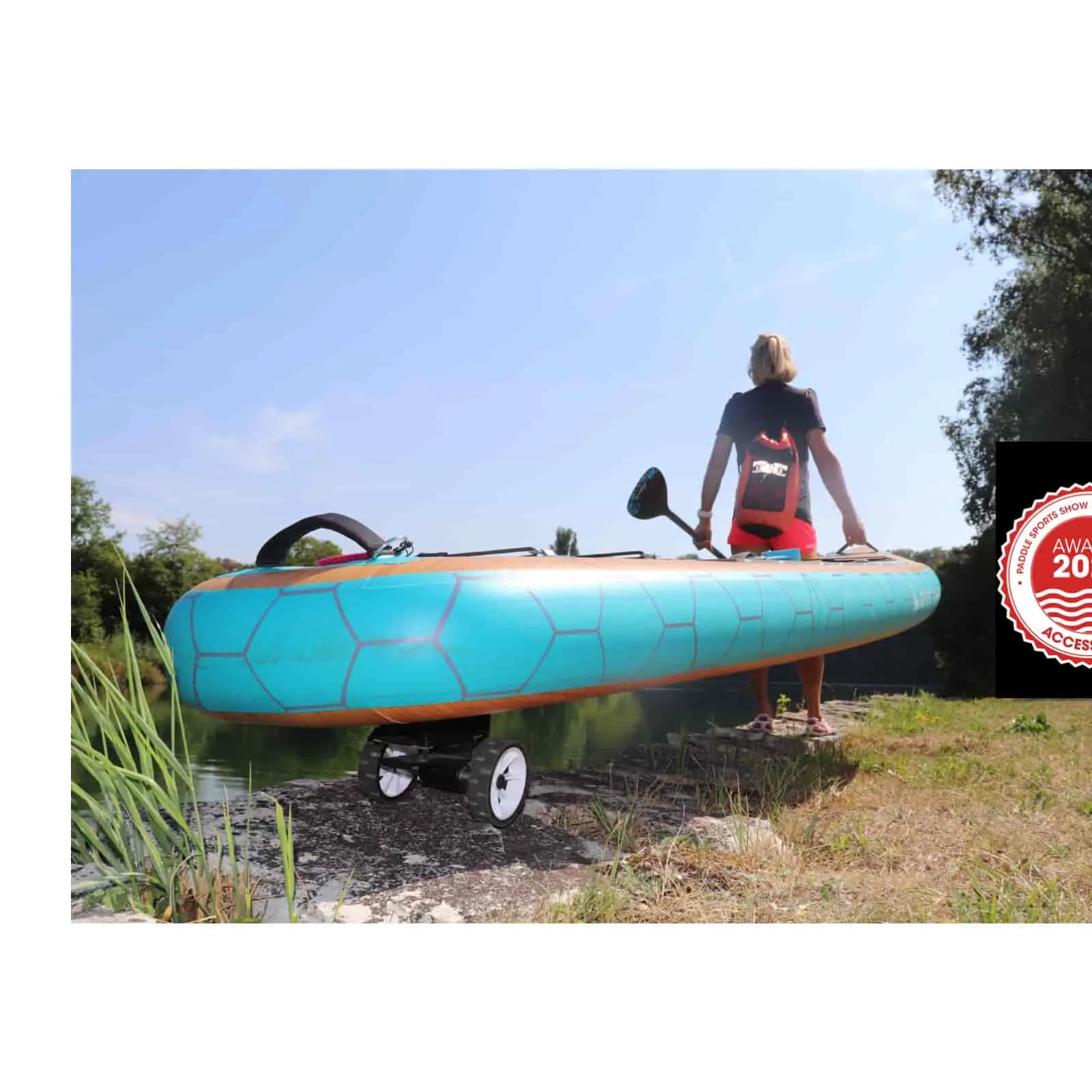 Blaues SUP Board mit SUPmover Rädern, getragen von Person. Paddel wird gehalten.
