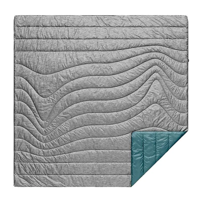 Quadratische, gesteppte Rumpl Puffy Blanket in hellgrau mit wellenförmigem Muster und türkisfarbener Ecke.