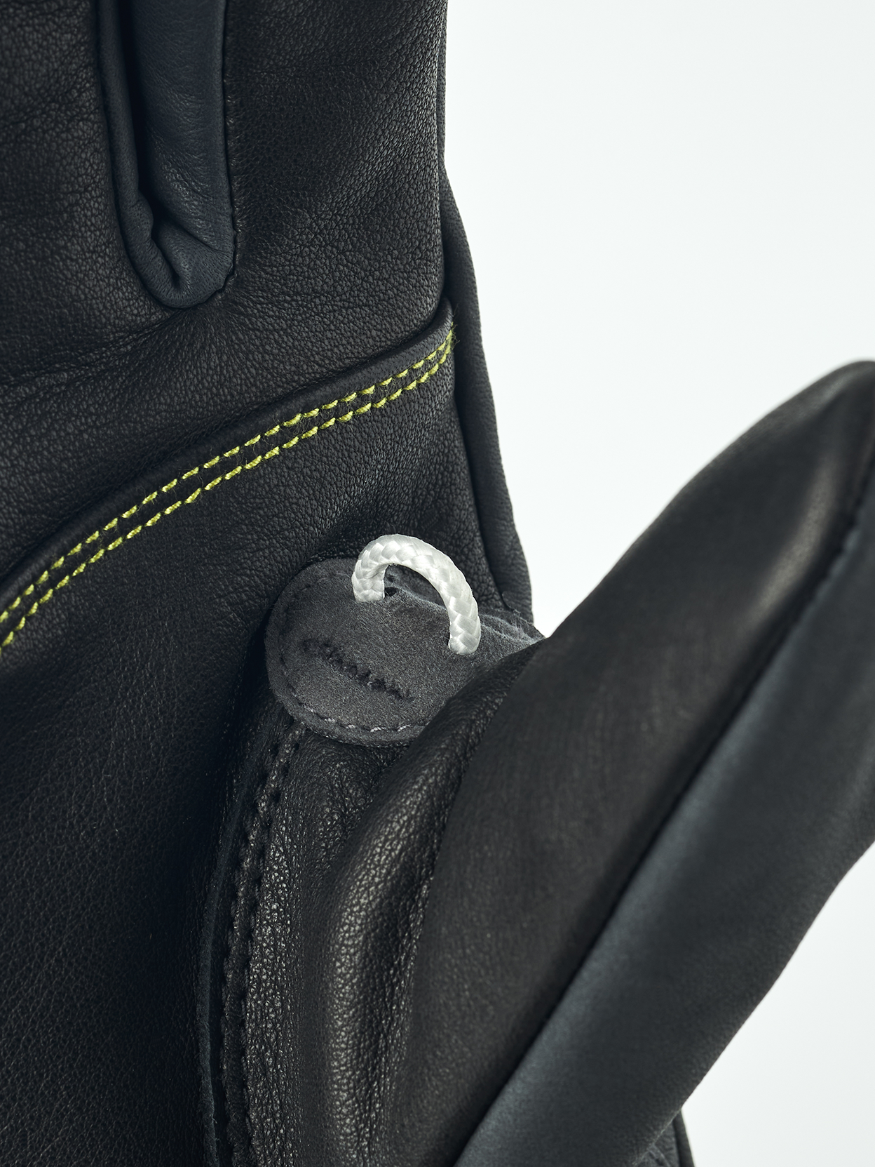 Detailansicht eines schwarzen Hestra Omni Trigger Handschuhs mit Schlaufe und gelber Naht.