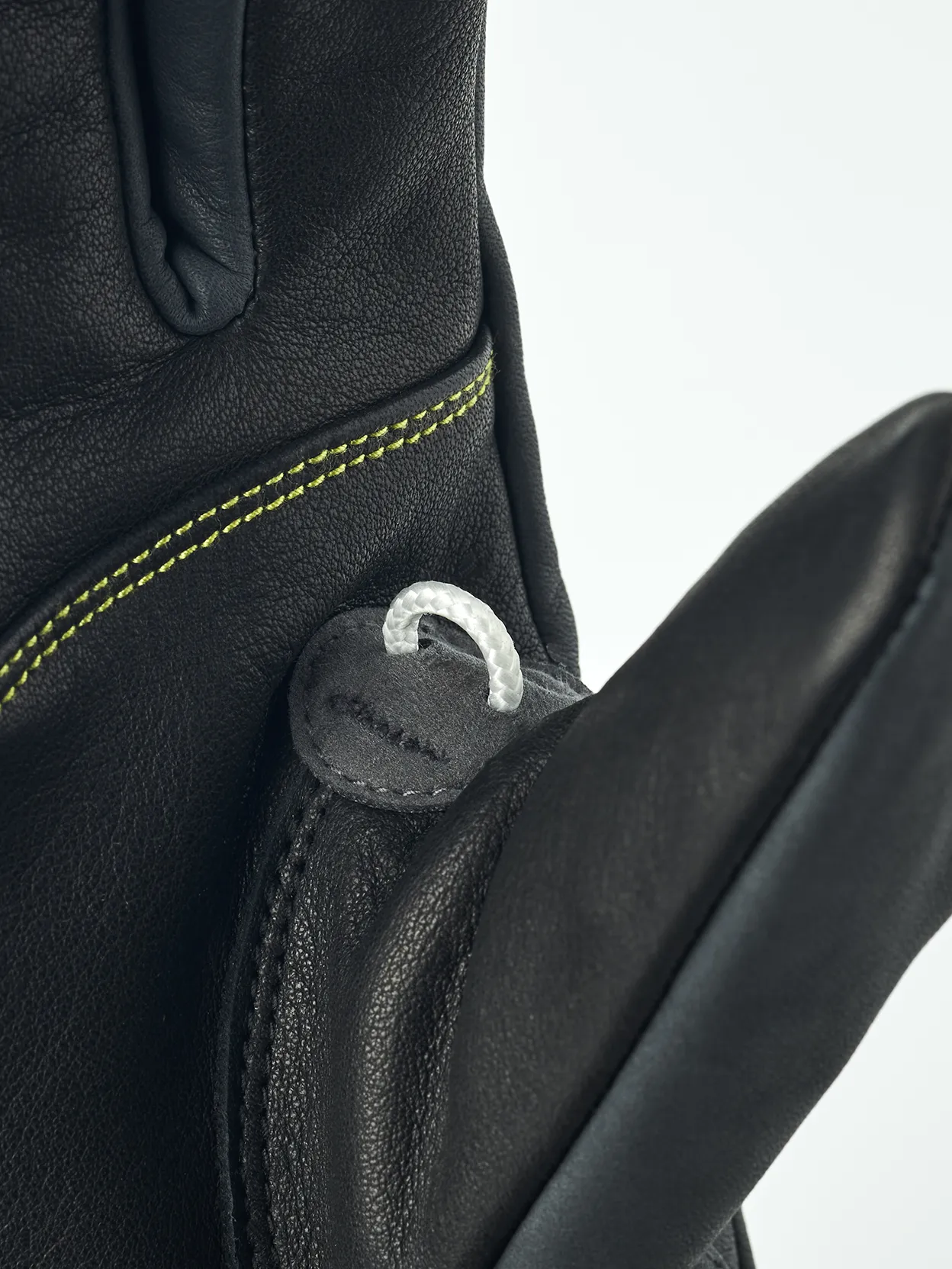 Detailansicht eines schwarzen Hestra Omni Trigger Handschuhs mit Schlaufe und gelber Naht.