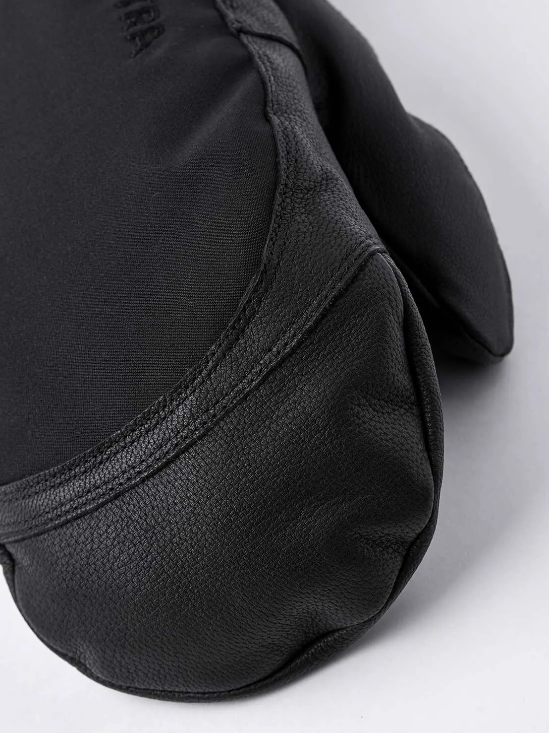 Nahaufnahme eines schwarzen Hestra Army Leather Extreme Mitt Fäustlings. Leder an der Handfläche, Textil am Handrücken.