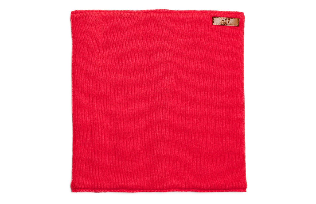 Roter, rechteckiger, gestrickter Neckwarmer mit kleinem Lederpatch in der oberen, rechten Ecke.