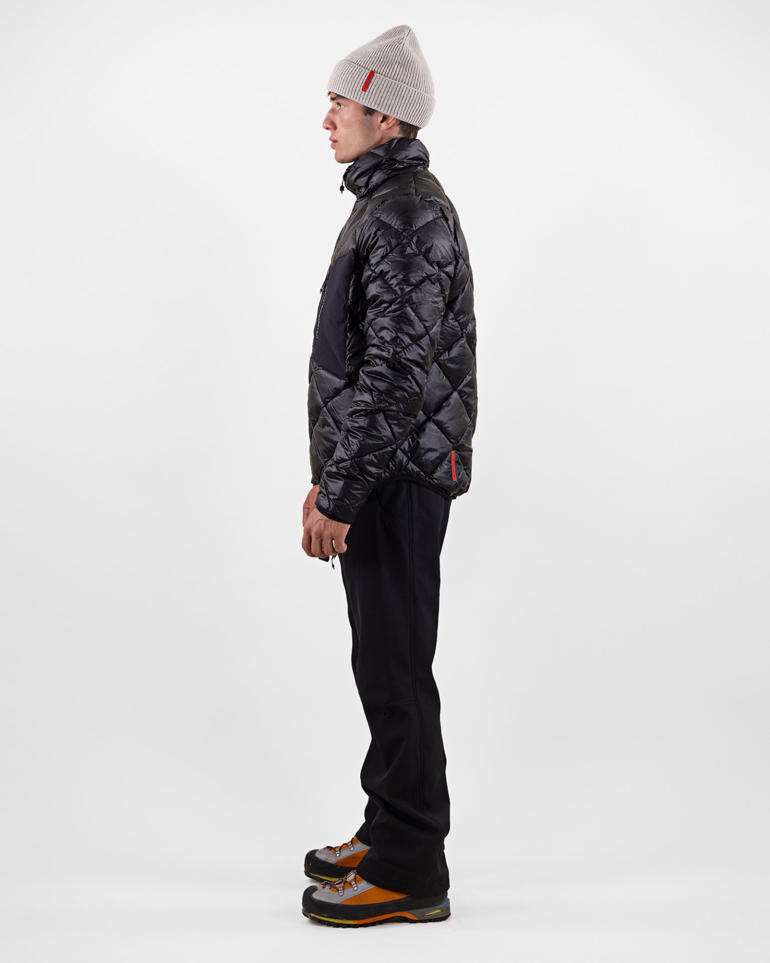 Ein Mann in Profilansicht trägt eine schwarze D-8 T Pertex Techno Daunenjacke, Hose und Mütze vor einem weißen Hintergrund.