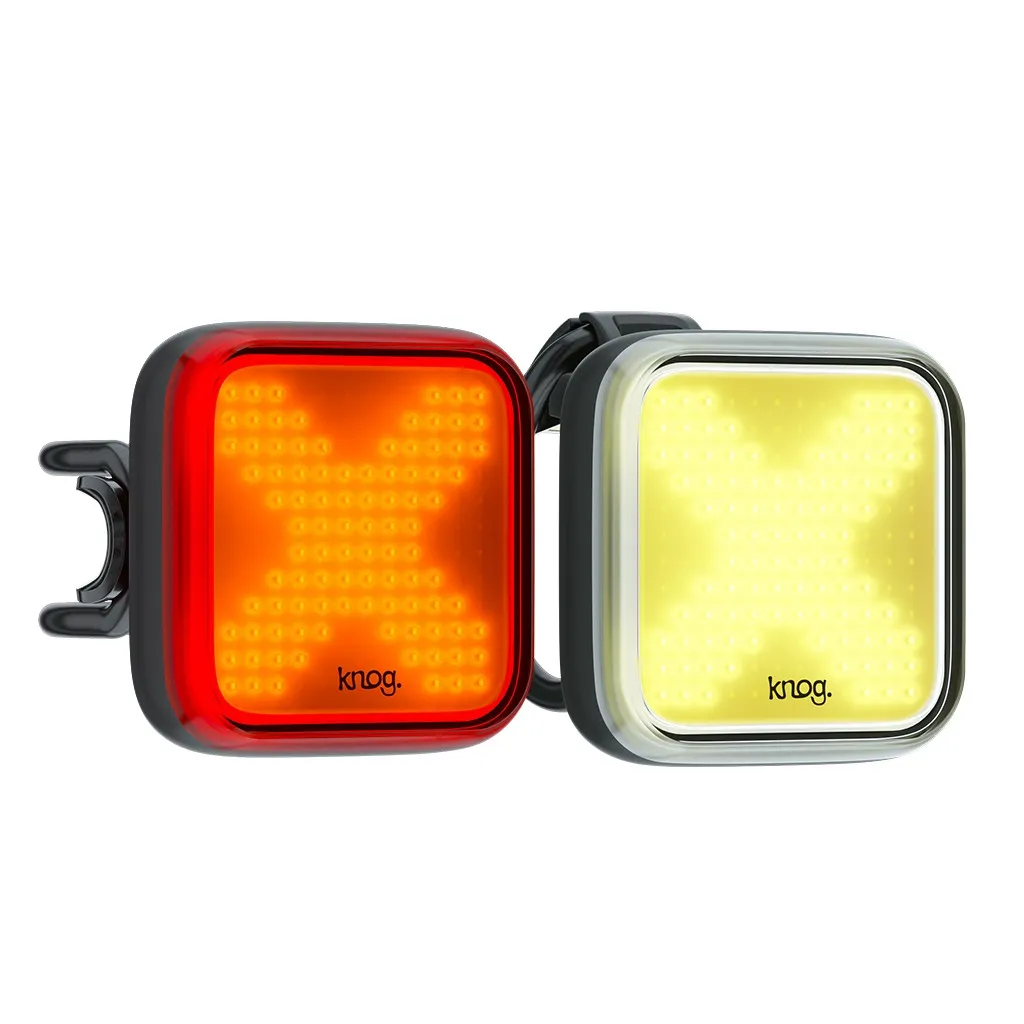 Lichtset Blinder X twinpack: Quadratische Fahrradlichter, rotes Rücklicht mit X-Muster, weißes Vorderlicht mit X-Muster.