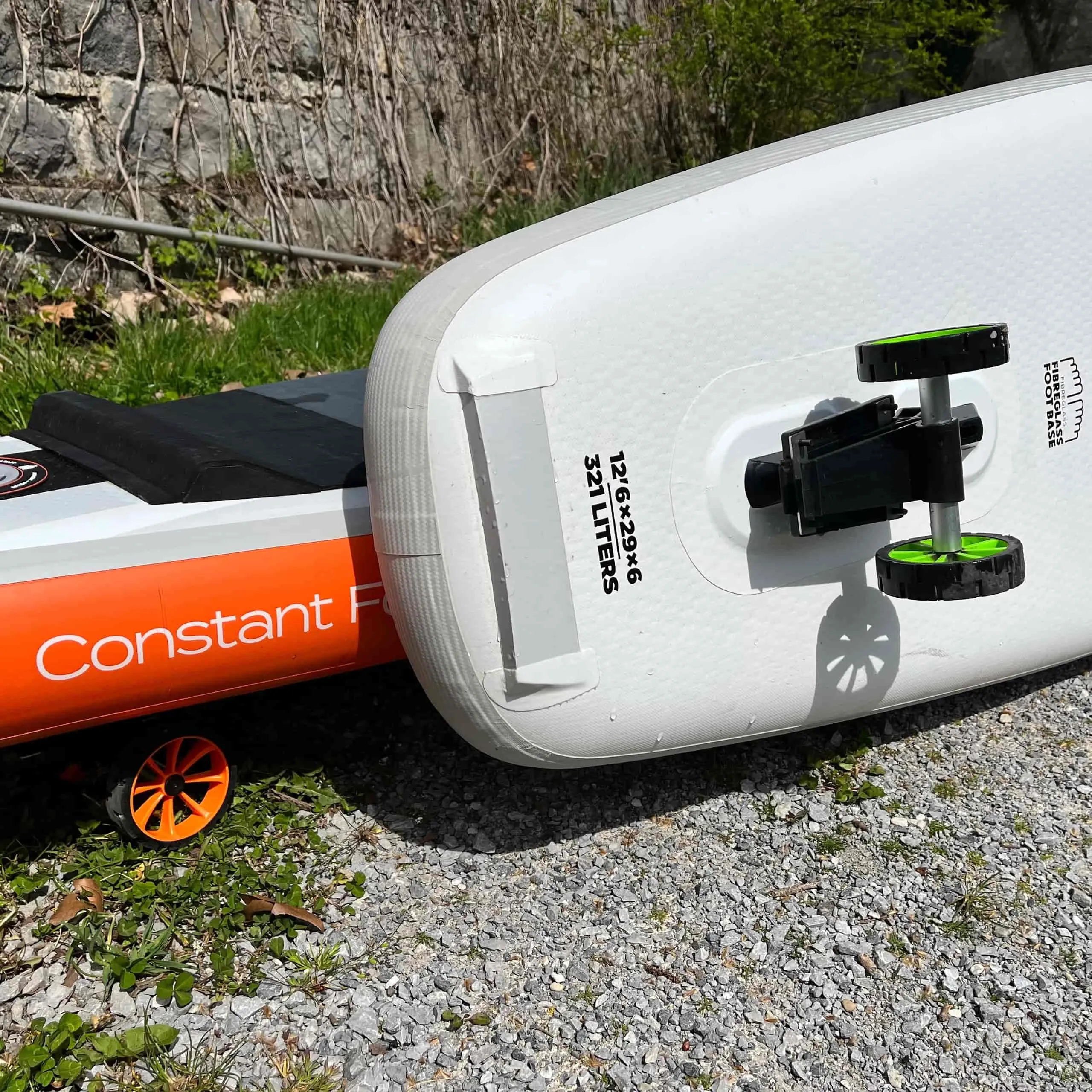 SUP Boards mit SUPmover Rädern. Das weiße Board hat grüne Räder, das orange Board hat orange Räder.