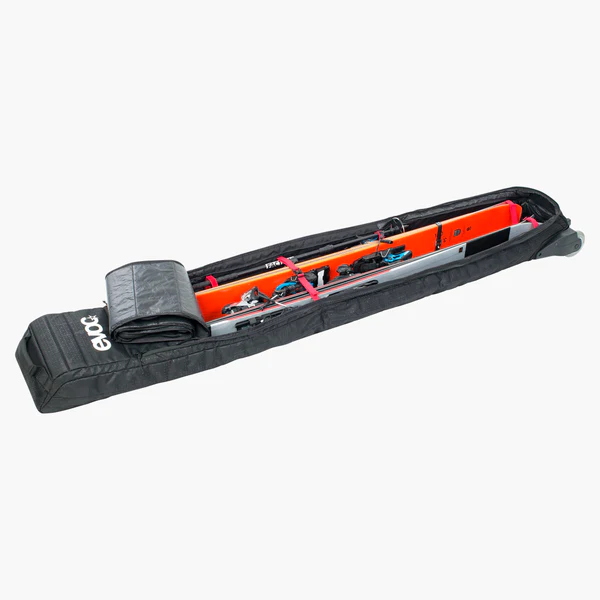 Evoc Ski Roller Schwarz Offener, schwarzer Evoc Ski Roller mit Skiern, Stöcken und Bindungen im Inneren, gesichert mit roten Gurten.