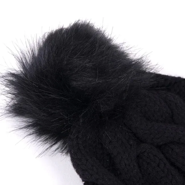 Nahaufnahme einer schwarzen, gestrickten Mütze mit großem, flauschigem Kunstfellbommel.